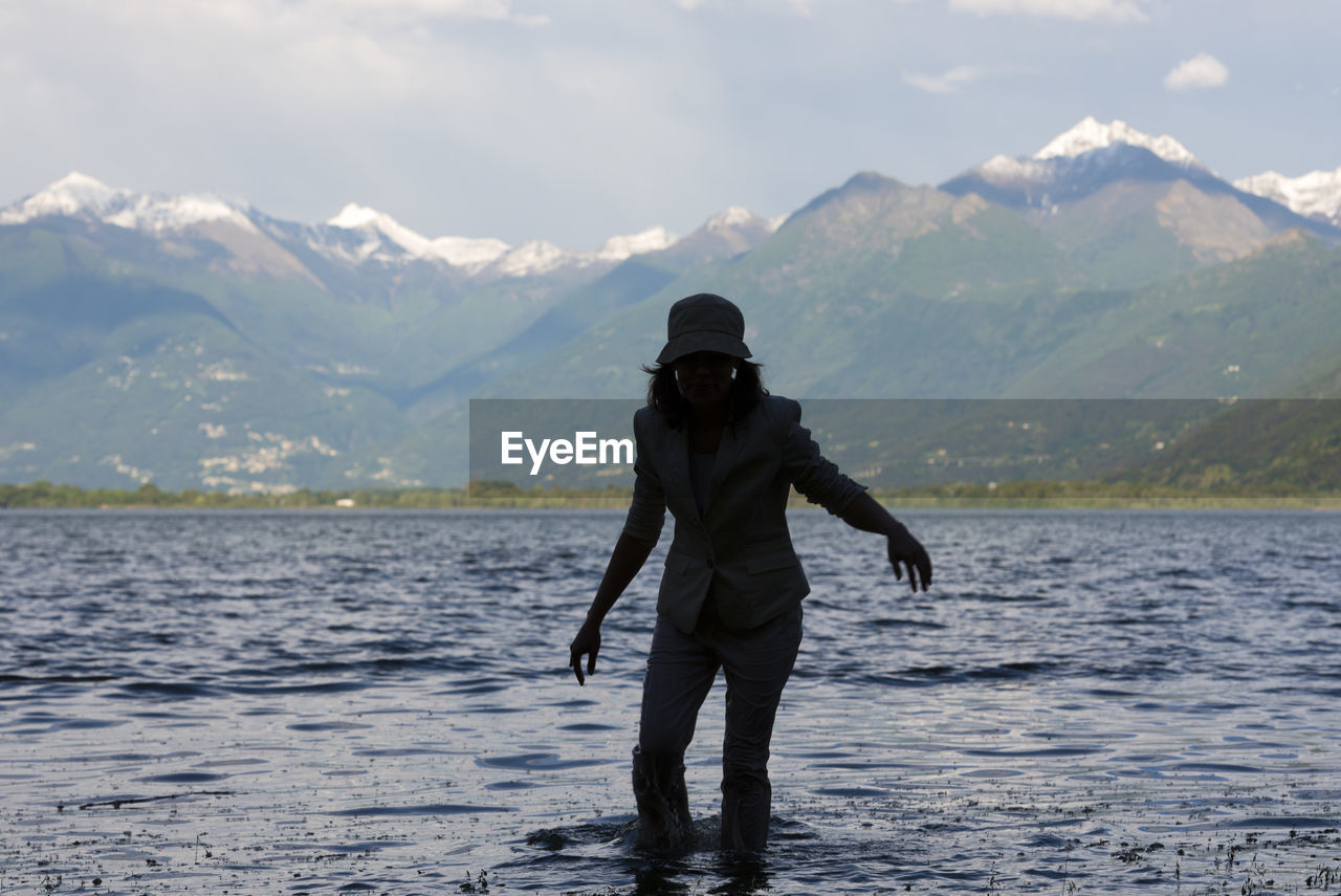 Woman standing in lake maggiore against mountains