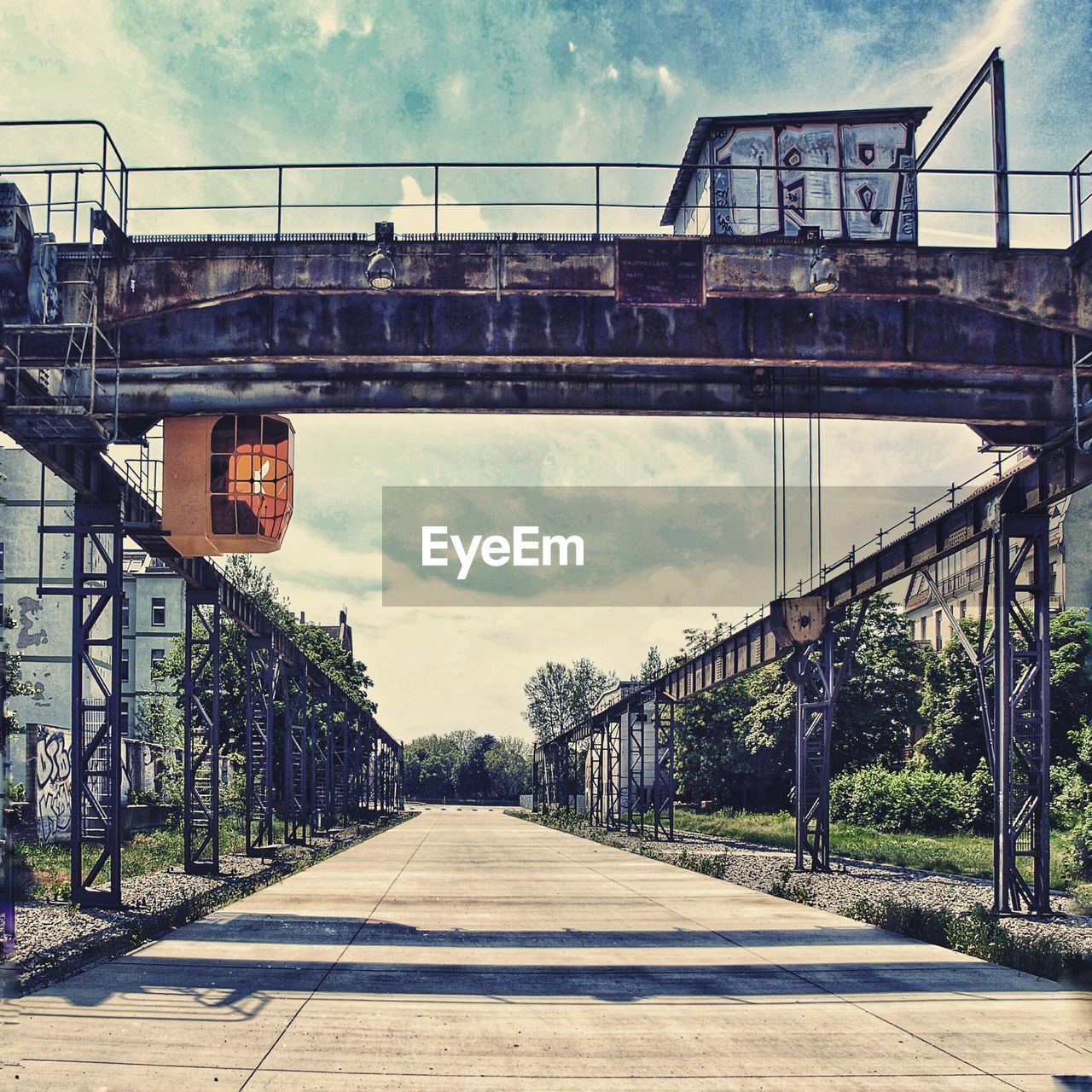 FOOTBRIDGE OVER RAILROAD TRACK AGAINST SKY