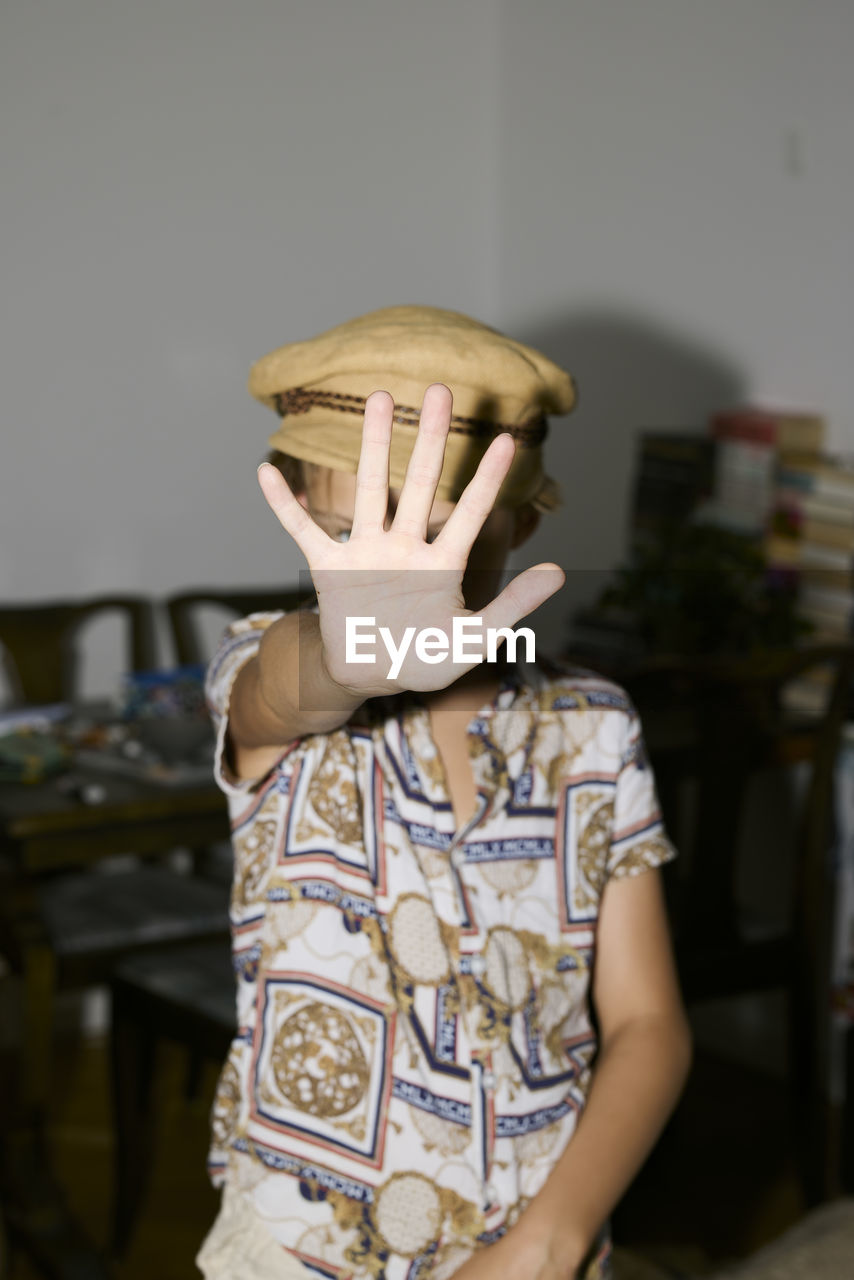 Boy with hand in front of face