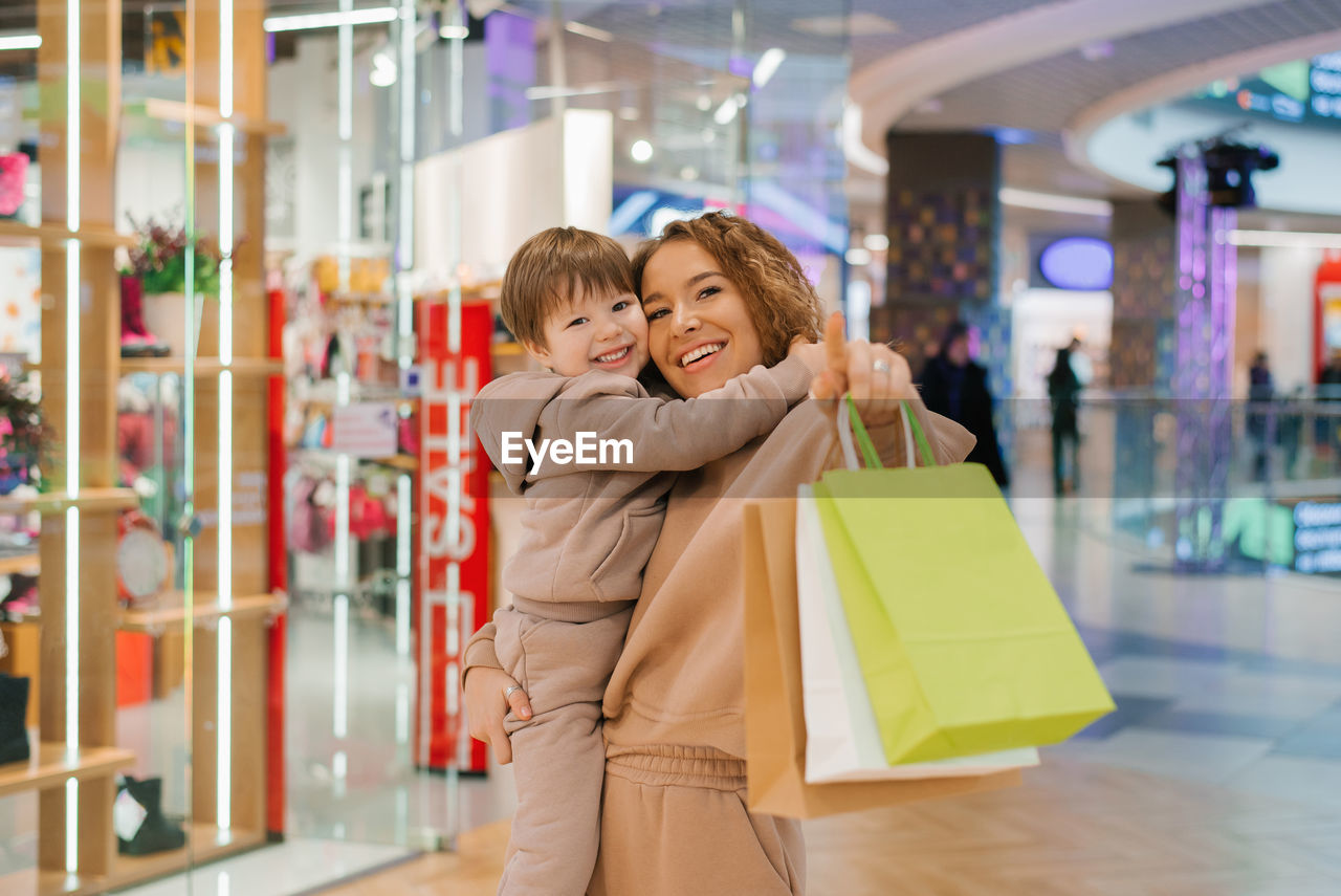 Happy and satisfied mother and little boy child with shopping bags in the store. go shopping