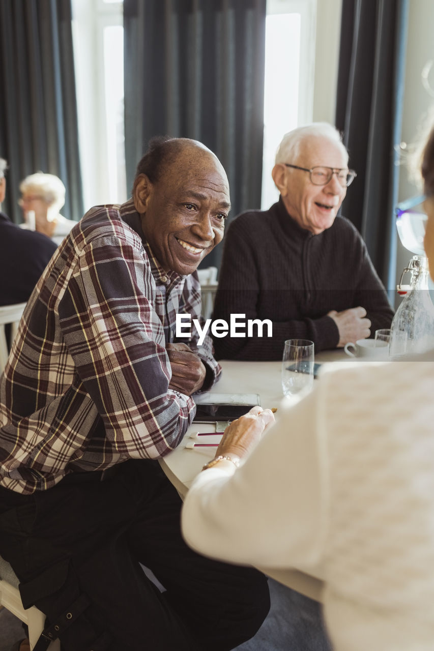 Smiling senior man talking with friend in nursing home