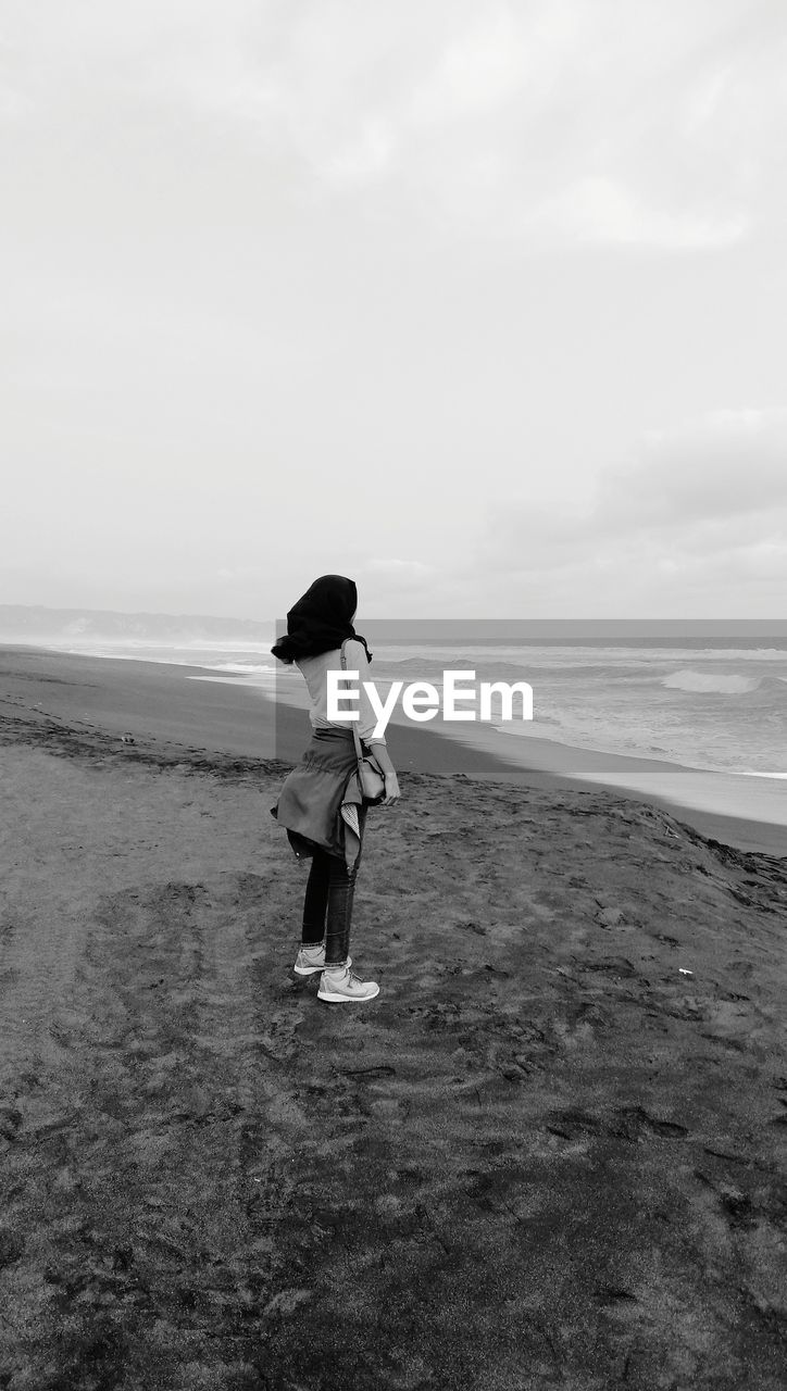 Full length of man standing on beach against sky