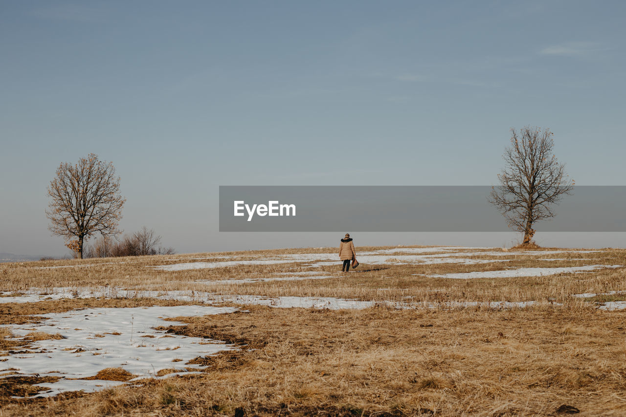 Woman on field against sky during winter