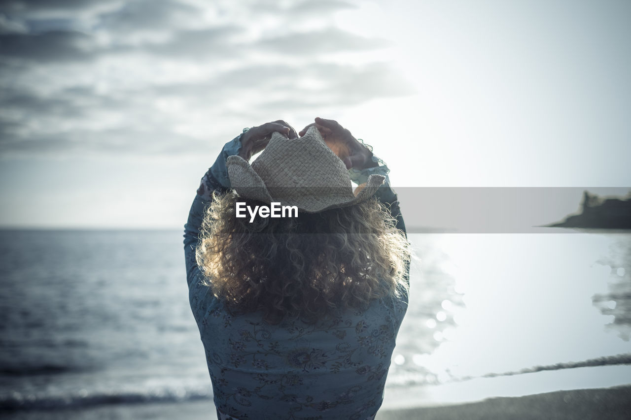 Rear view of woman looking at sea against sky