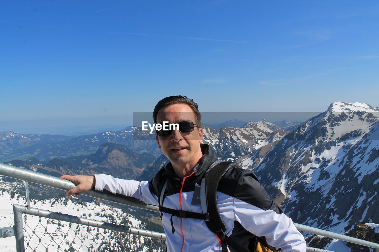 Close-up of man standing by railing against sky