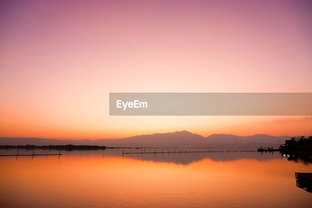 SCENIC VIEW OF LAKE AGAINST ORANGE SKY