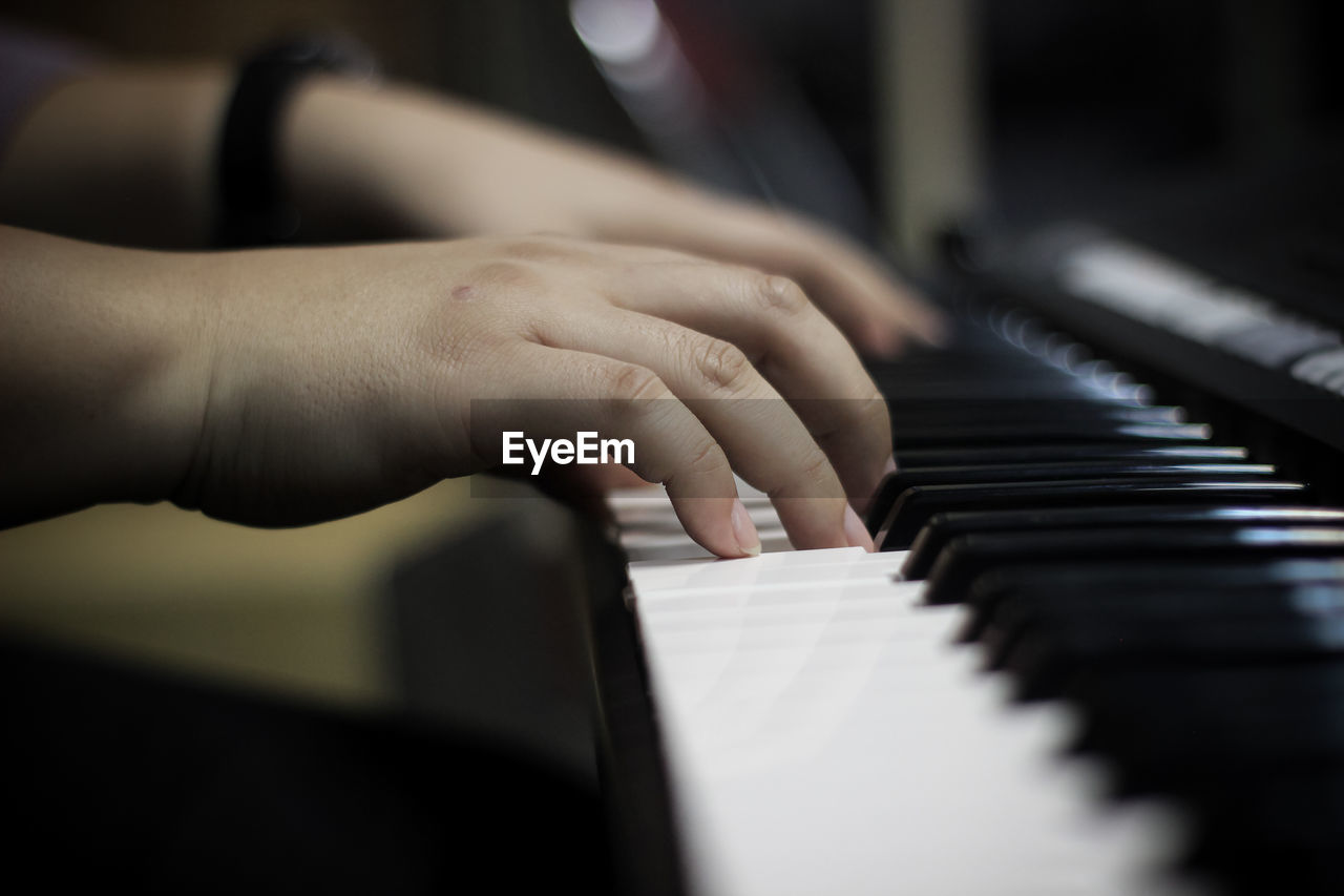 Cropped hands of person playing piano