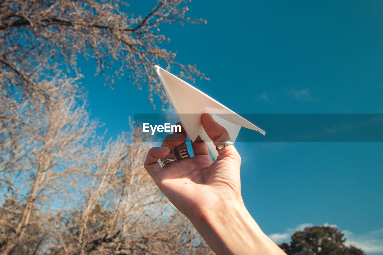 Person holding umbrella against blue sky