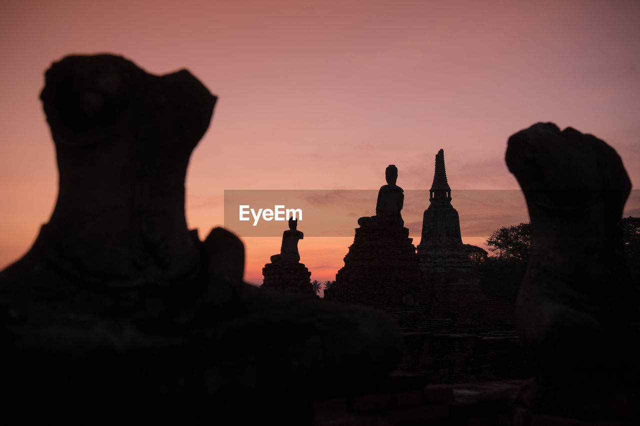 Low angle view of silhouette buddha statues against sky during sunset