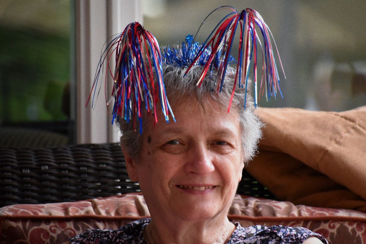 Close-up portrait of senior woman wearing colorful headwear on sofa
