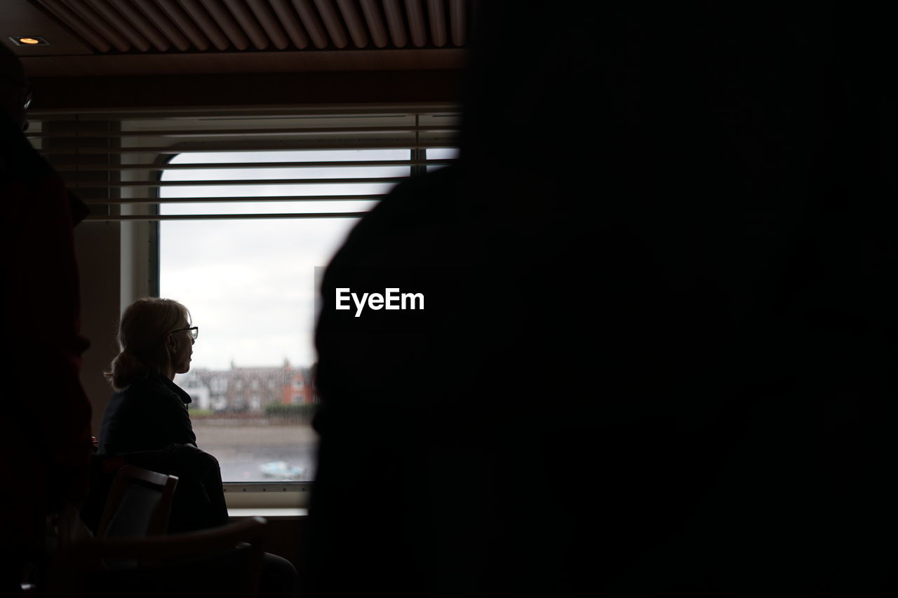 PORTRAIT OF A SILHOUETTE MAN SITTING IN WINDOW