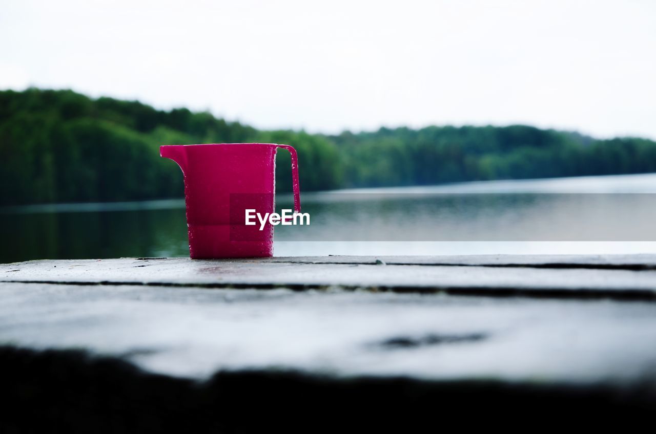 CLOSE-UP OF RED PIPE AGAINST LAKE