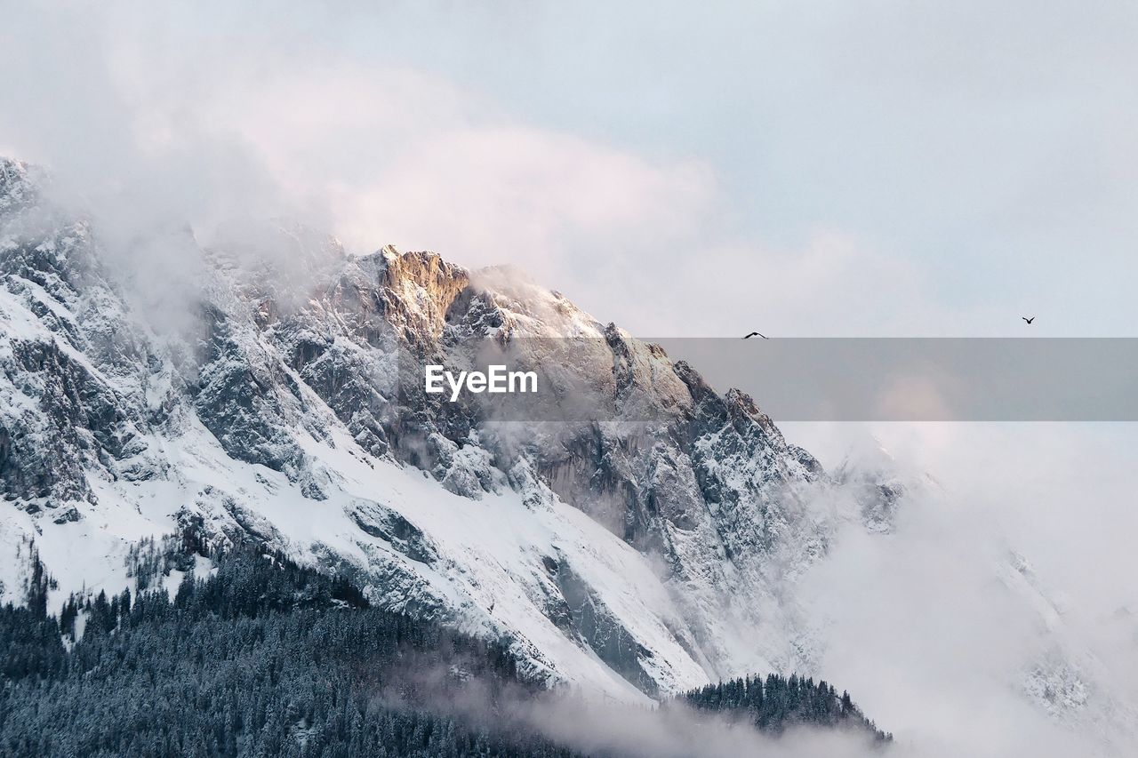 Low angle view of snowy mountain against sky during winter