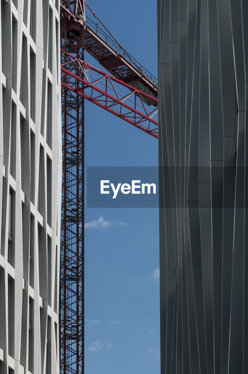 Low angle view of buildings and crane against sky