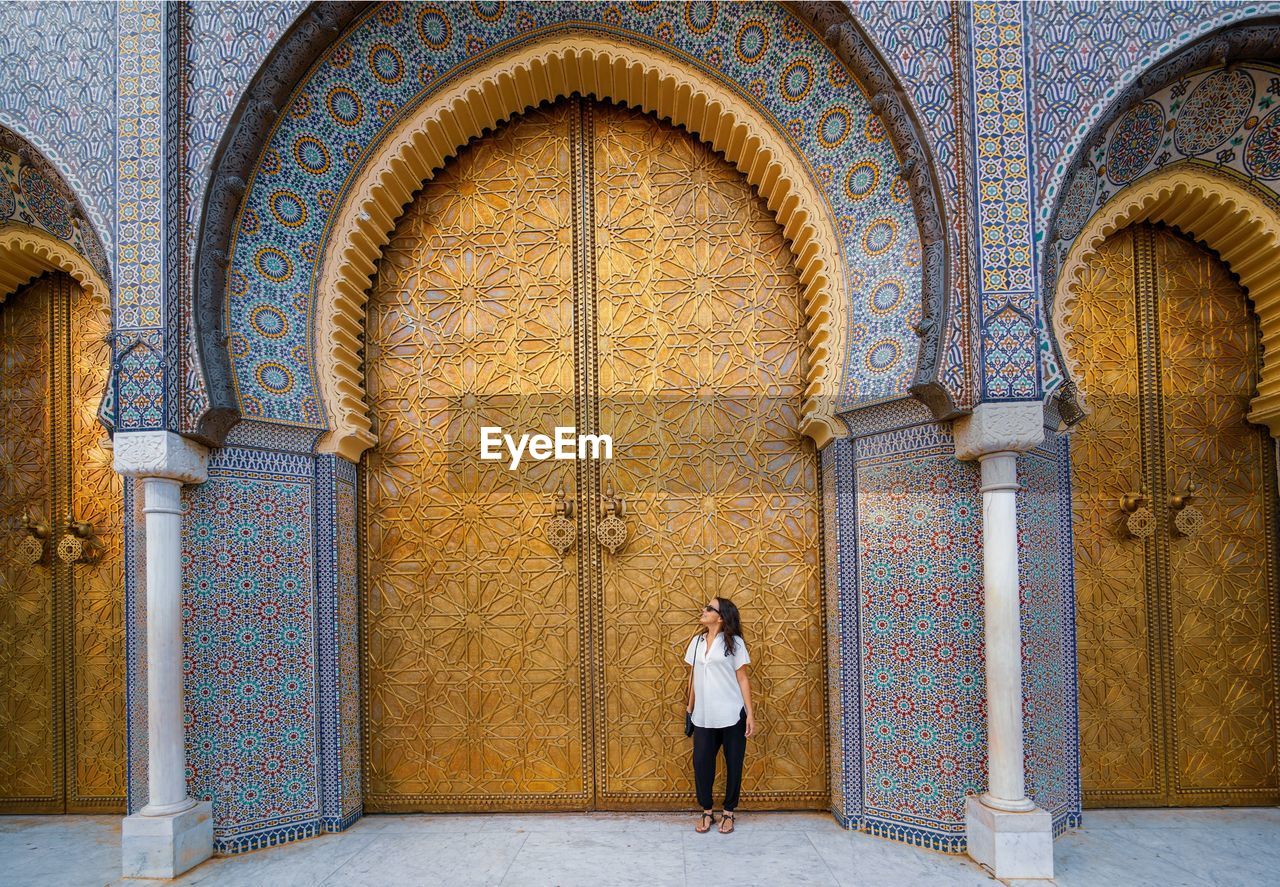 FULL LENGTH REAR VIEW OF WOMAN STANDING AT ENTRANCE OF HISTORIC BUILDING