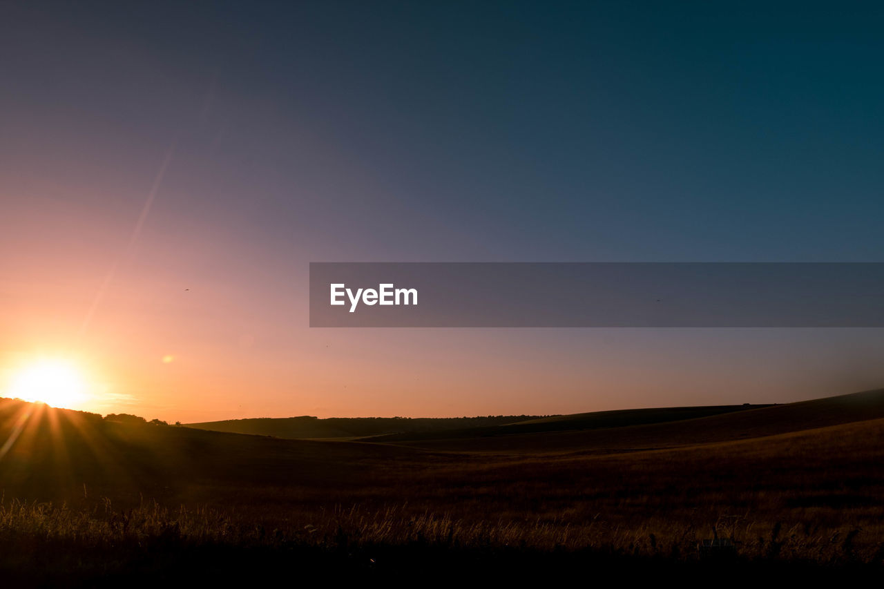 SCENIC VIEW OF FIELD AGAINST SKY DURING SUNSET