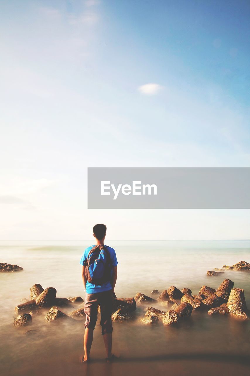 Rear view of traveler looking at seascape against sky