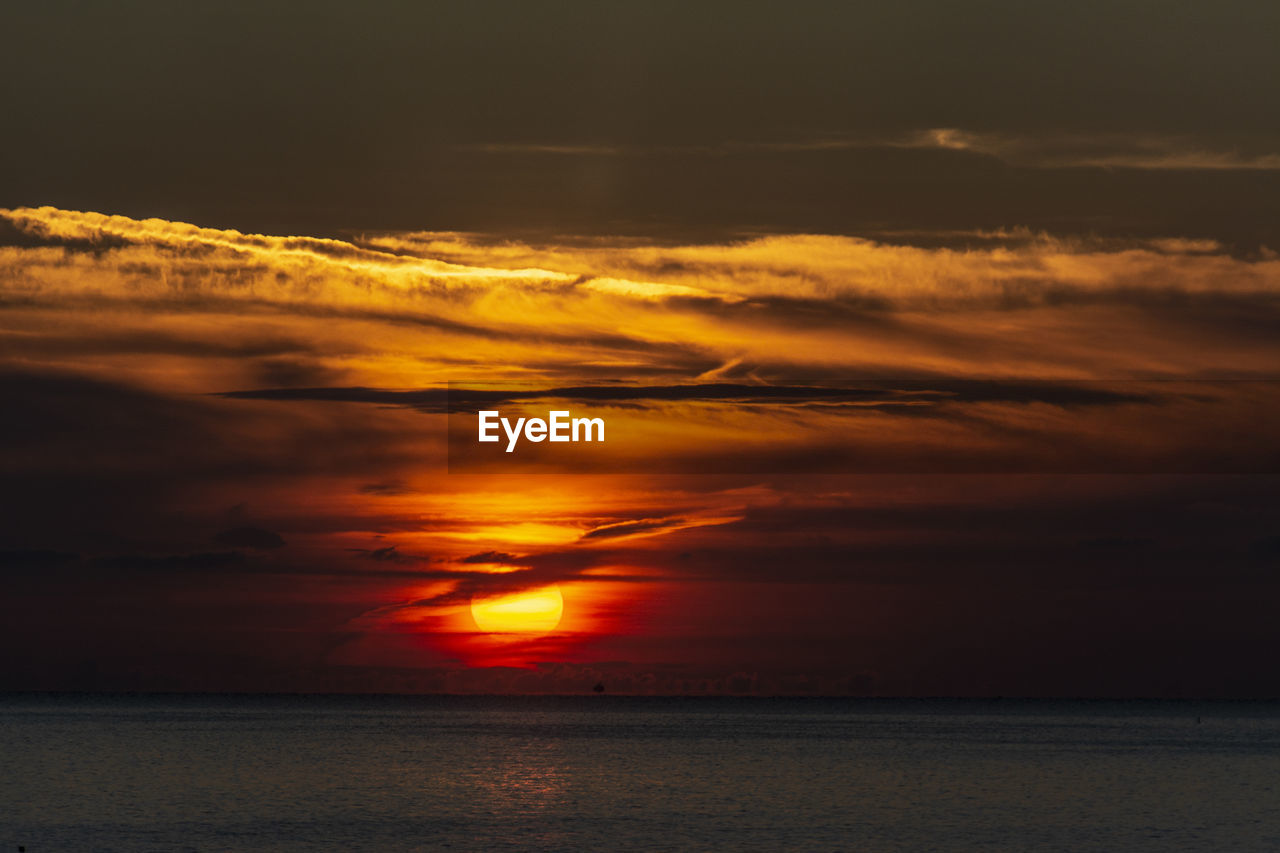 sky, sunset, cloud, beauty in nature, water, sea, scenics - nature, tranquility, nature, tranquil scene, dramatic sky, horizon over water, afterglow, horizon, orange color, idyllic, no people, seascape, environment, ocean, red sky at morning, outdoors, sunlight, reflection, beach, atmospheric mood, sun, land, coast, cloudscape, evening, awe, non-urban scene, landscape, travel