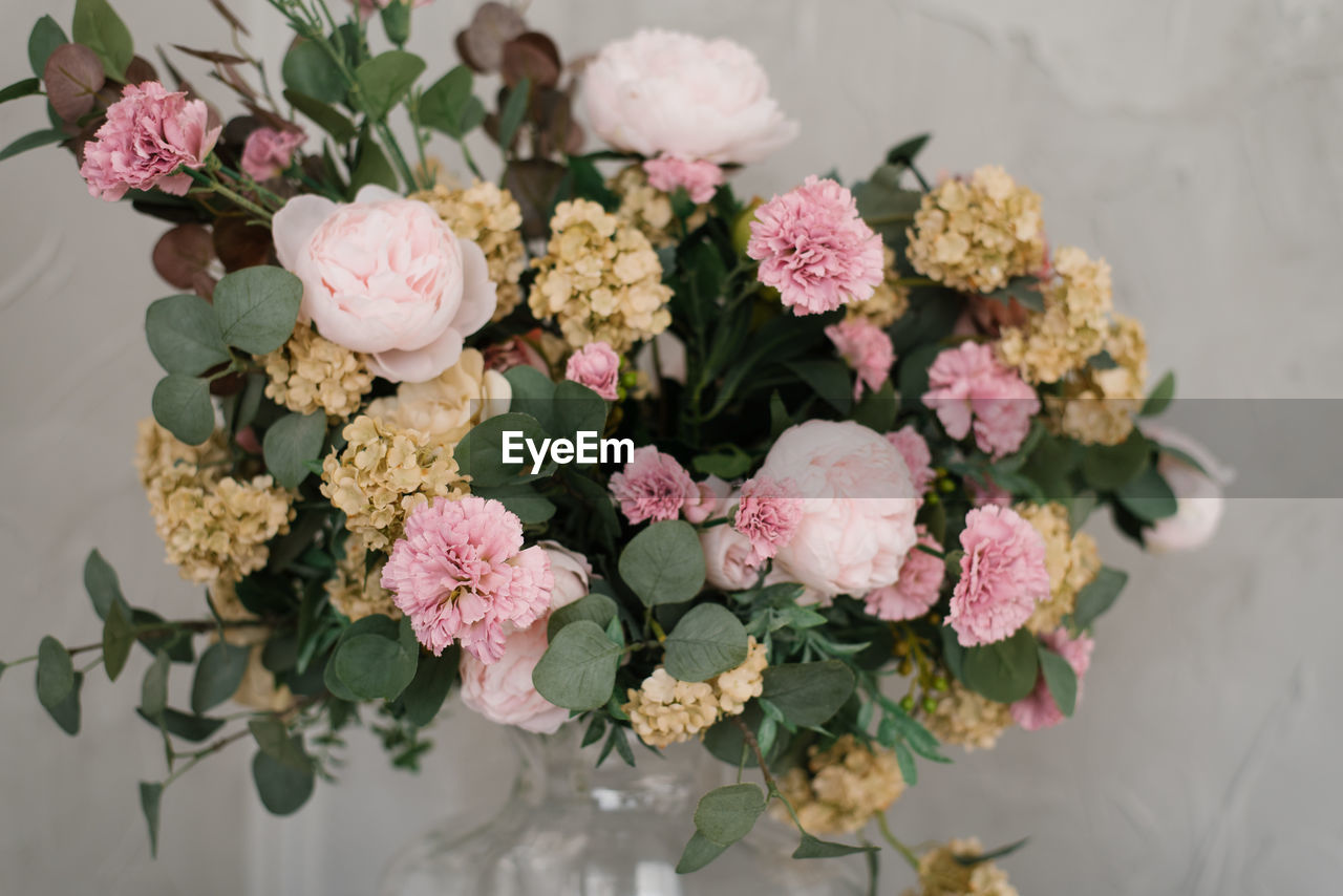 A luxurious bouquet of flowers in a glass transparent vase in the interior decor of the house