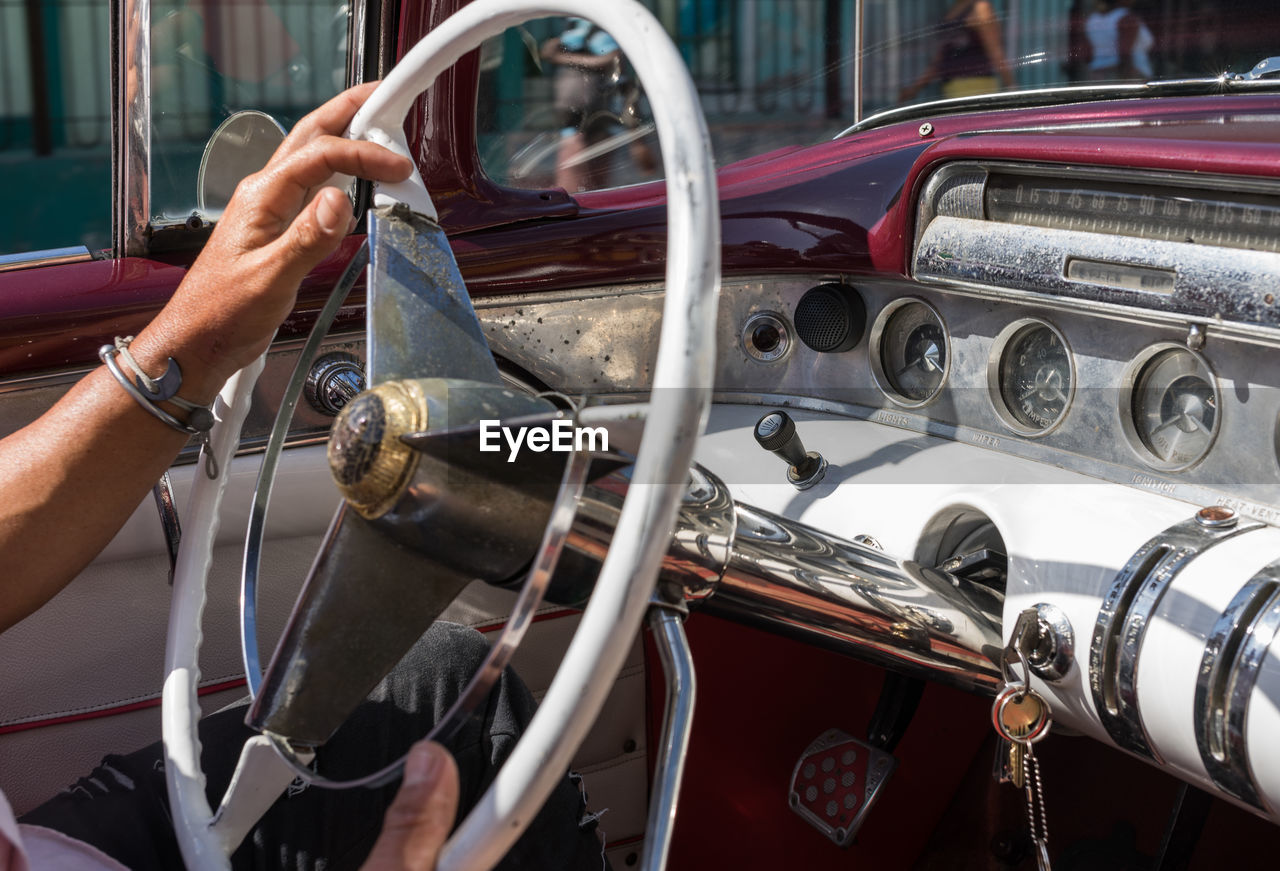 car, vehicle, motor vehicle, mode of transportation, antique car, transportation, vintage car, land vehicle, hand, one person, steering wheel, adult, luxury vehicle, wheel, automobile, auto show, control panel, retro styled, day, automotive exterior, dashboard