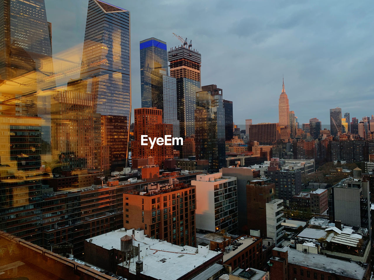 Hudson yards and empire state building in nyc during evening, with reflection of sunset lights.