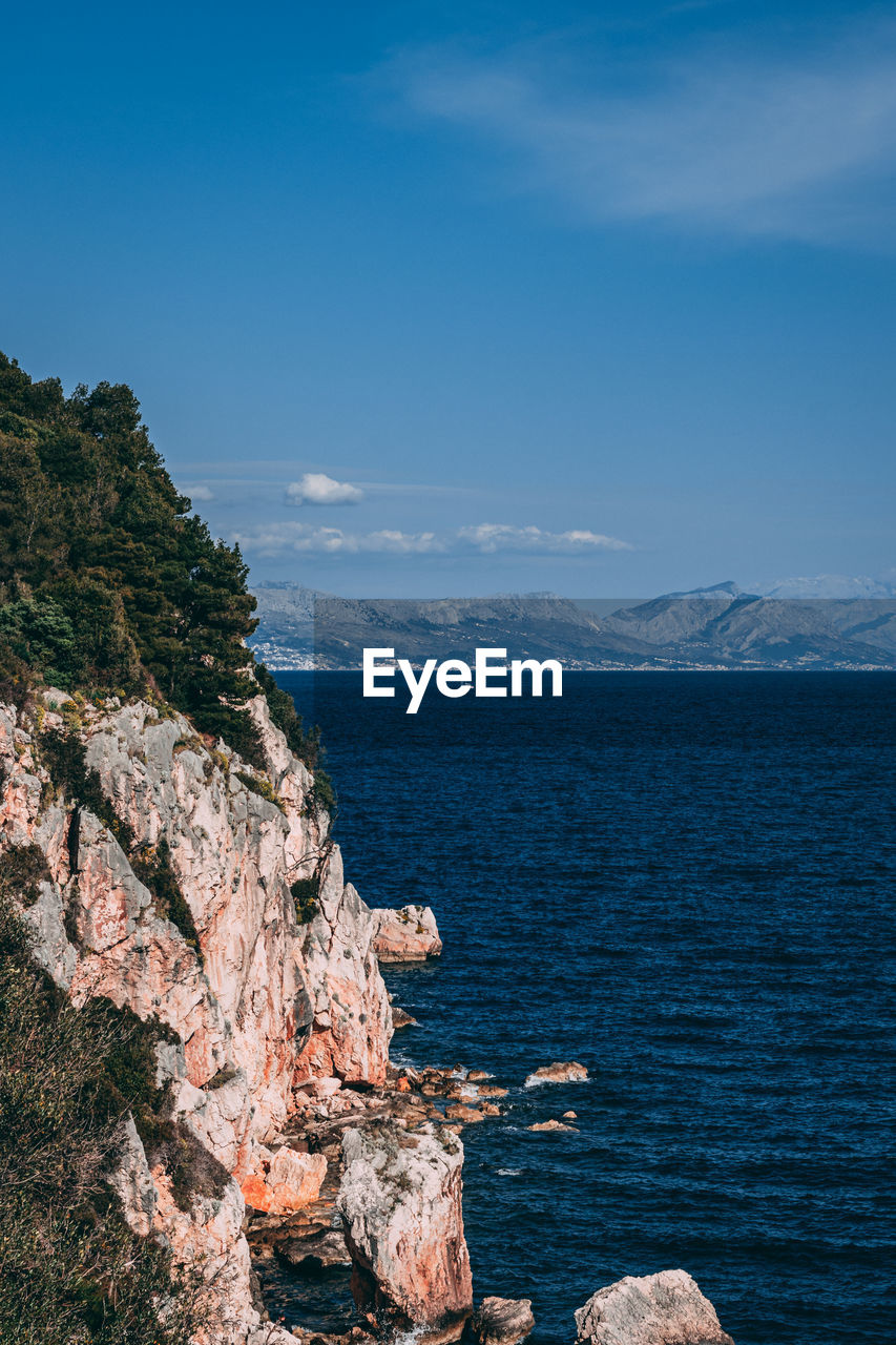 Scenic view of sea and rocks against blue sky