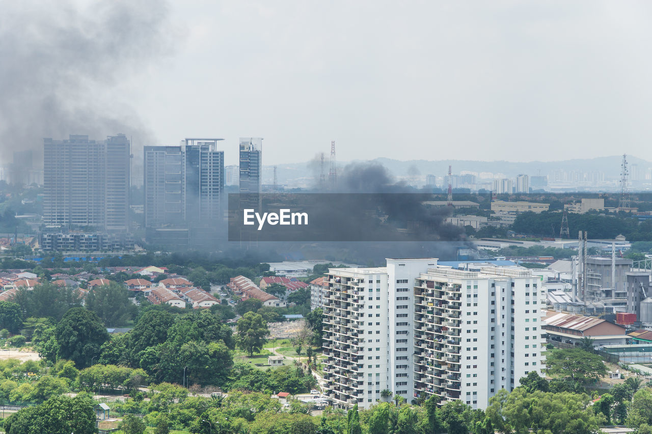 Smoke amidst cityscape against sky