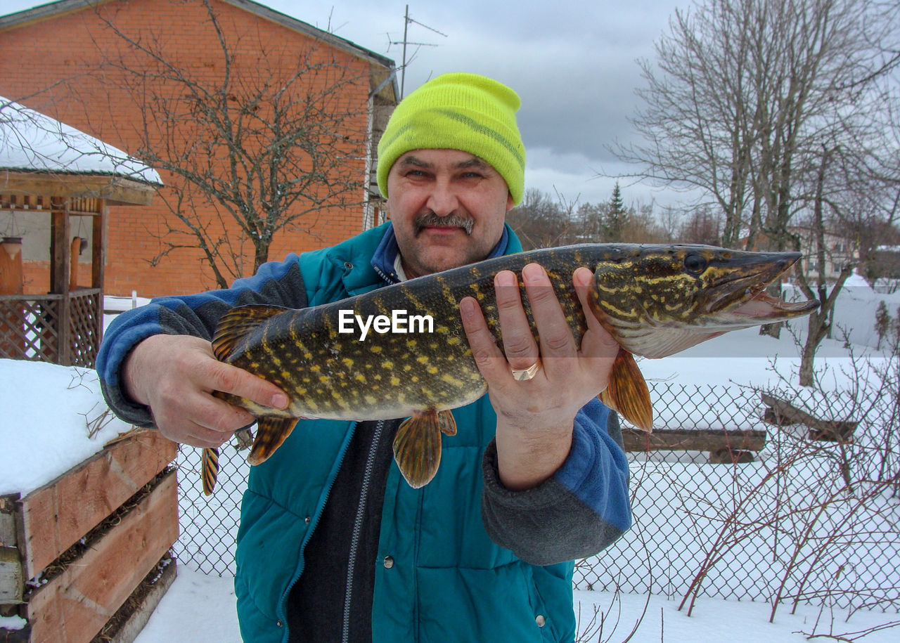 Happy fisherman with pike in his hands