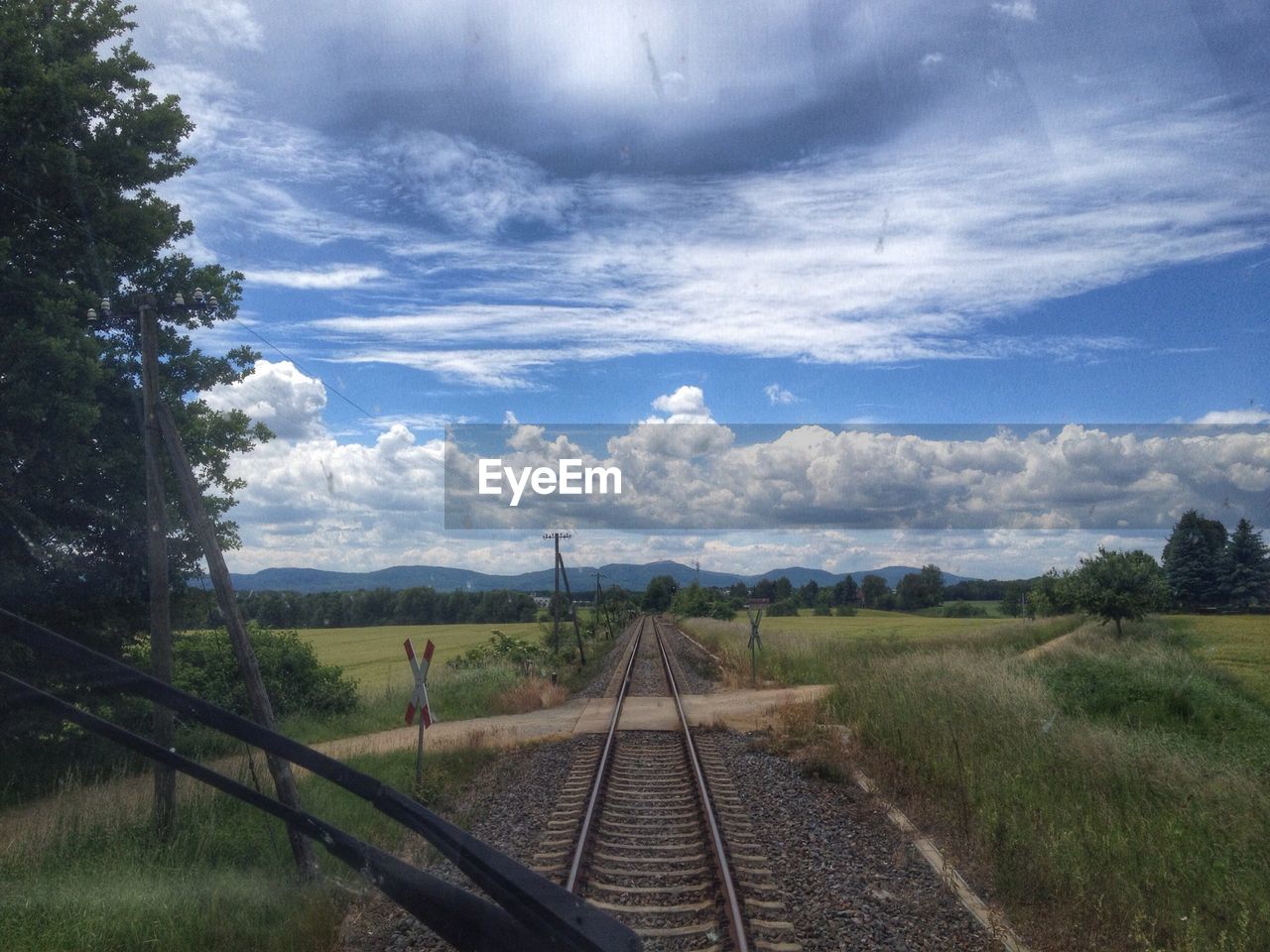 Railway tracks surrounded by grassy landscape seen through train windshield