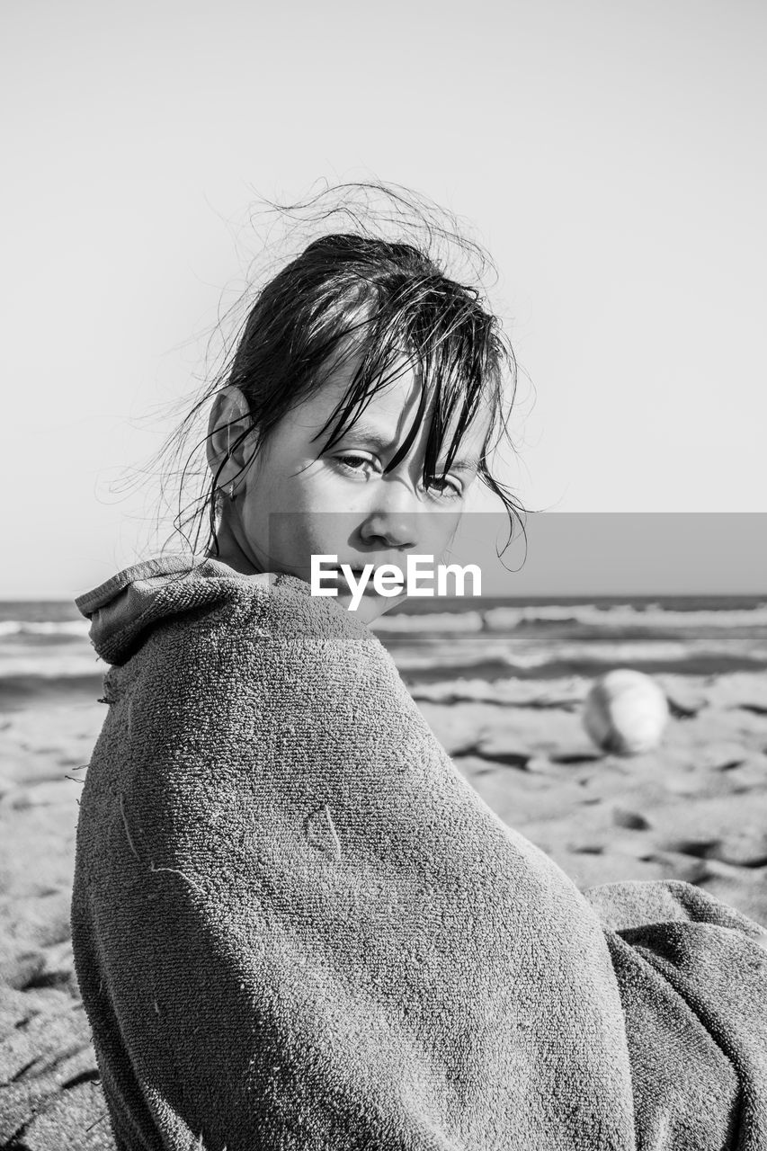 Portrait of girl standing at beach against clear sky