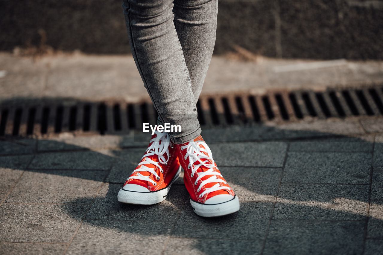 Low section of woman standing on footpath