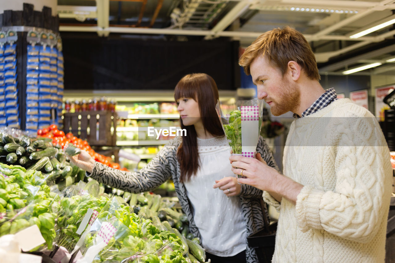 Young couple selecting vegetables at supermarket