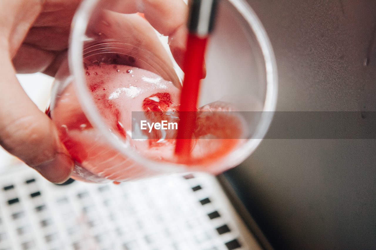 Cropped image of hand pouring red beer in glass