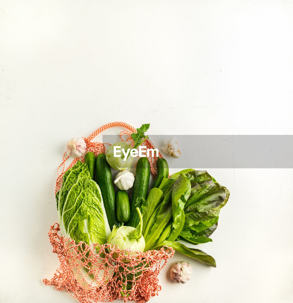 Assorted teen vegetables in a string bag on white background., top view. healthy diet concept