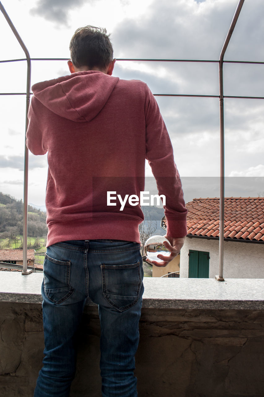 Rear view of man standing by window