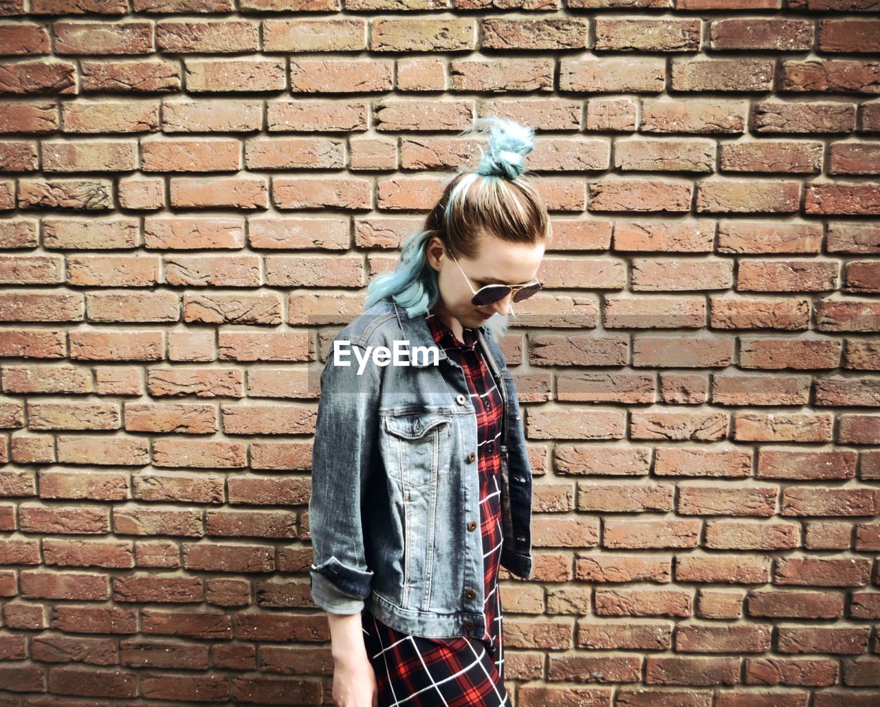 Young woman standing against brick wall