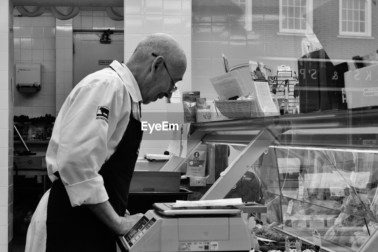 SIDE VIEW OF MAN WORKING AT STORE