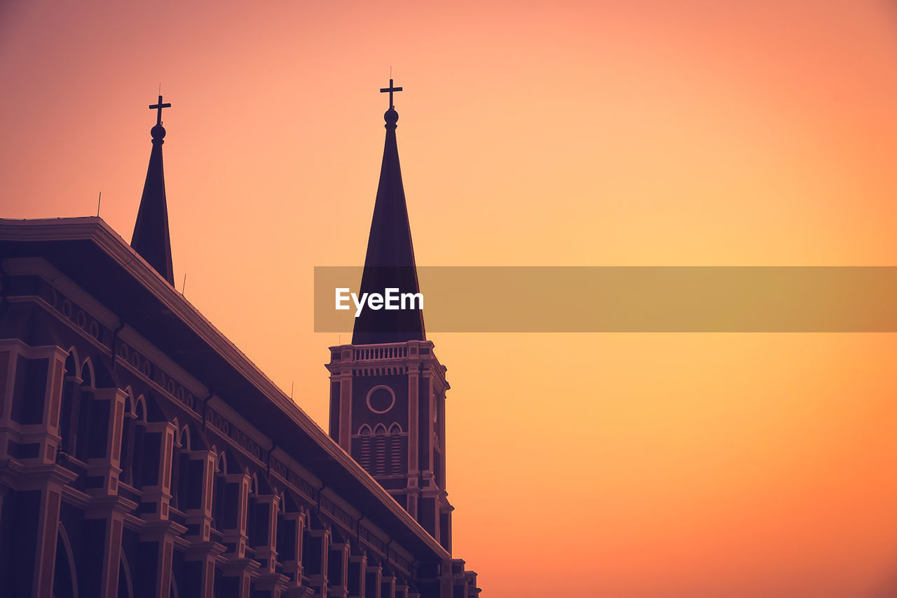 LOW ANGLE VIEW OF ILLUMINATED BUILDING AGAINST SKY DURING SUNSET