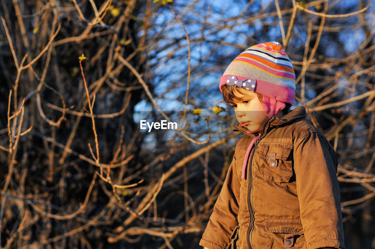 Girl in warm clothing against bare trees