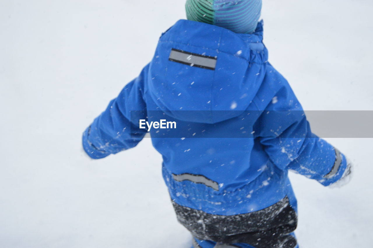 Rear view of boy walking on snow