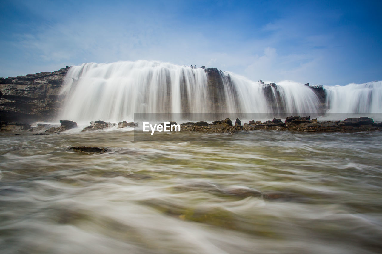 Low angle view of waterfall against sky