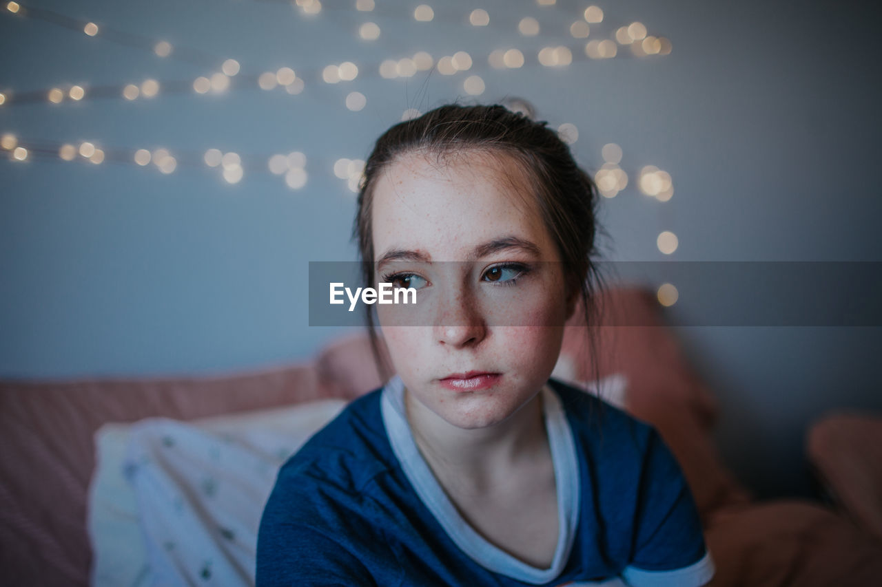 Content tween sitting on bed looking out window