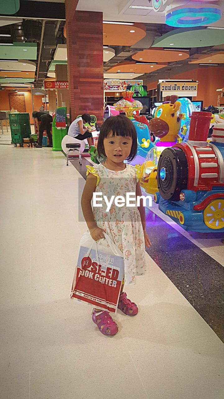 PORTRAIT OF SMILING GIRL STANDING IN STORE