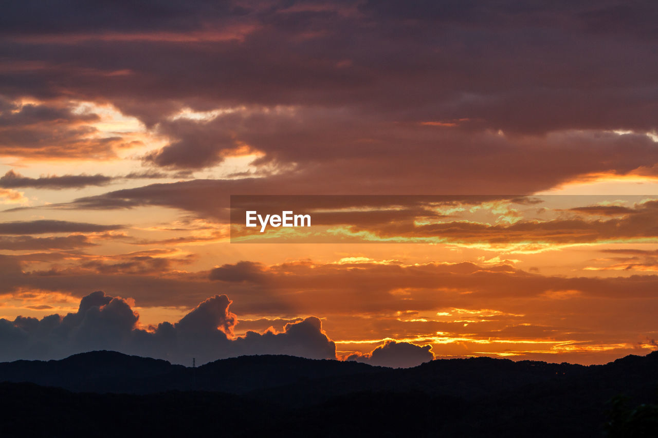 Idyllic shot of silhouette mountains against orange cloudy sky during sunset