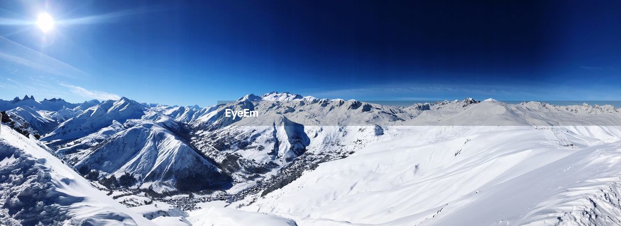 Scenic view of snowcapped mountains against blue sky