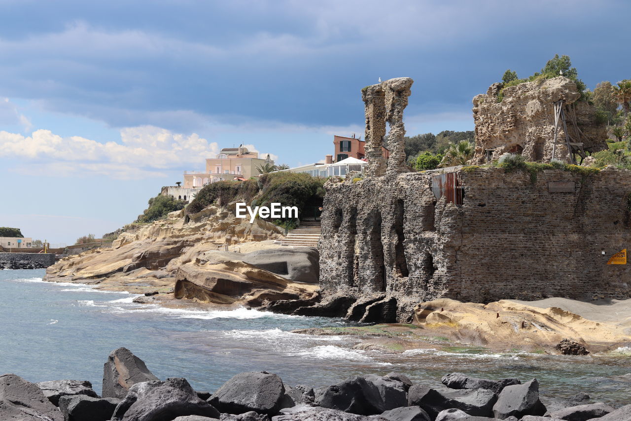 coast, rock, sky, sea, water, land, vacation, architecture, nature, cloud, travel destinations, beach, history, cliff, ruins, built structure, travel, the past, ocean, shore, terrain, no people, building, outdoors, tourism, coastline, building exterior, scenics - nature, day, ancient, environment, old ruin, beauty in nature, rock formation, bay, tower, ancient history