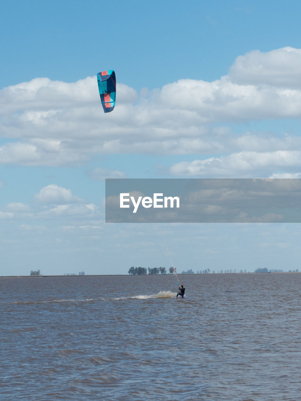 Person paragliding in sea against sky