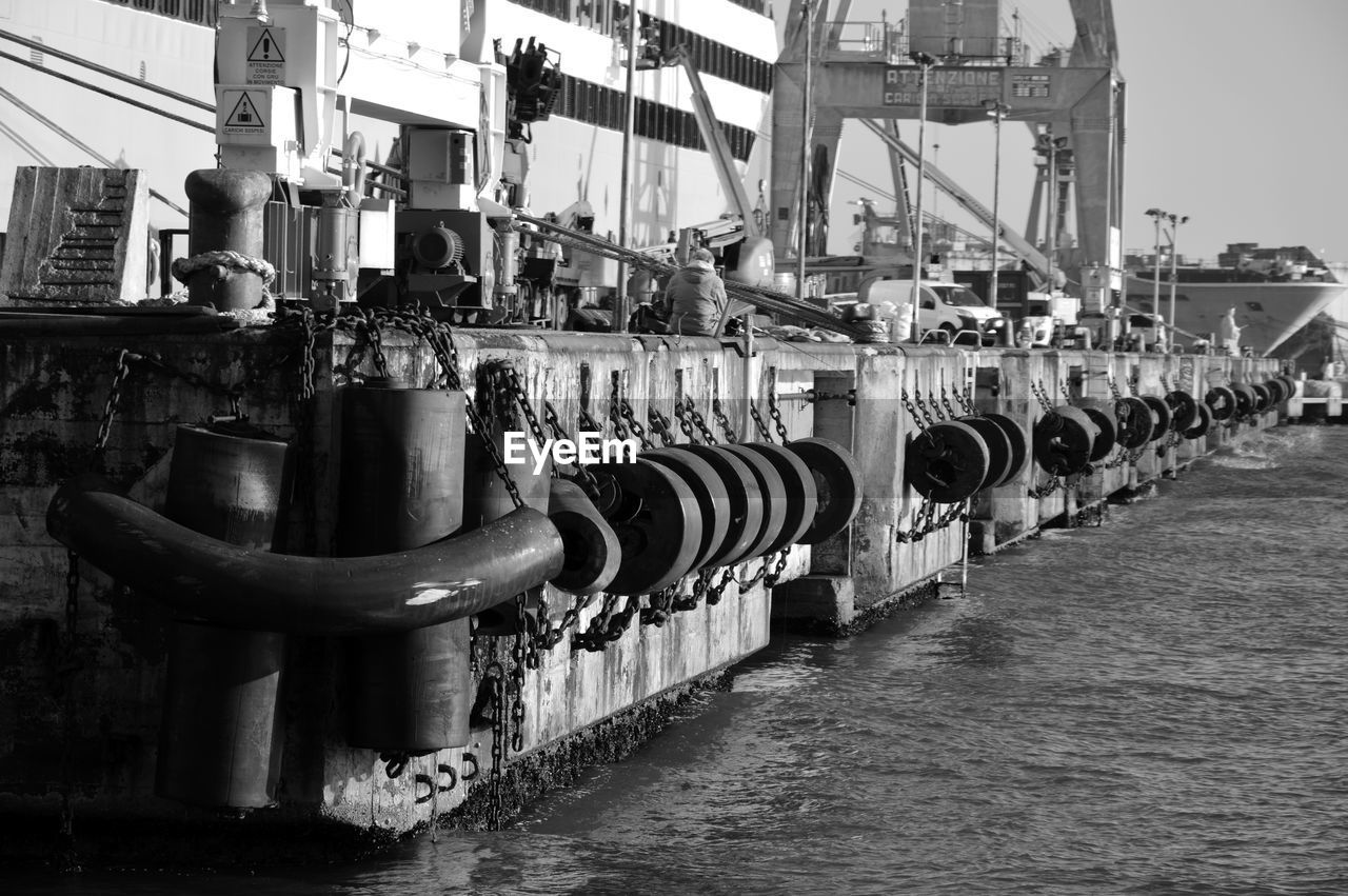 Row of rubber tires hanging from chain by pier in sea at commercial dock