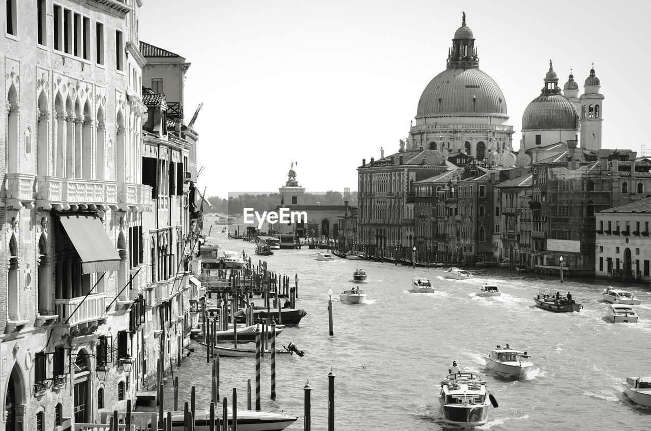 Boats sailing on grant canal by santa maria della salute against clear sky