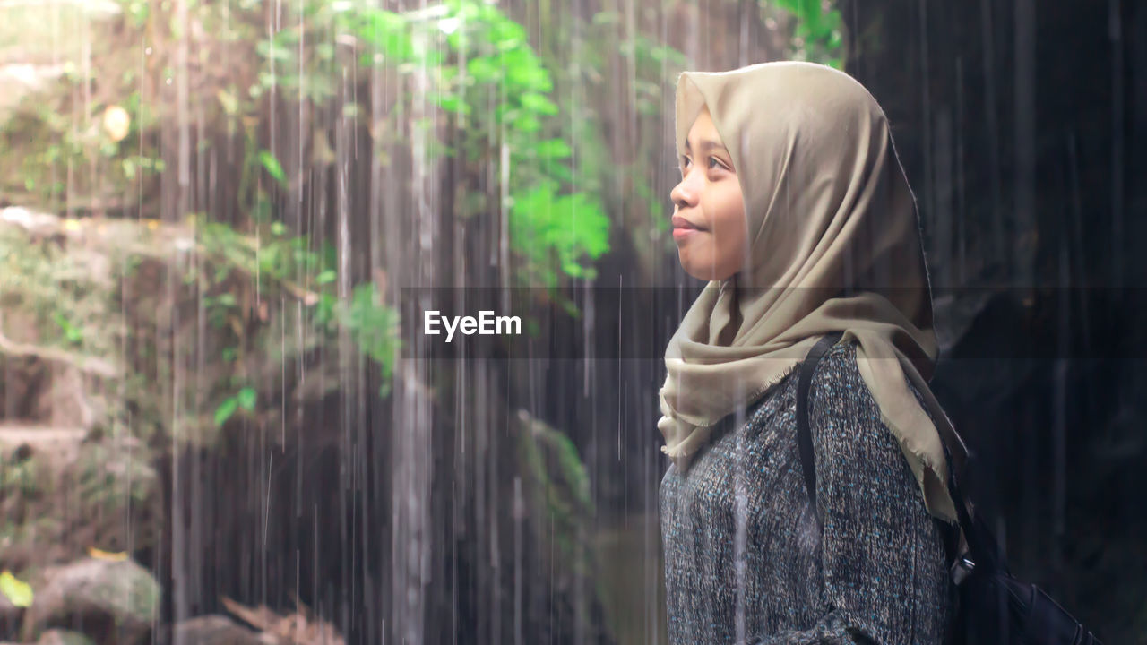 Side view of young woman wearing headscarf while standing in forest